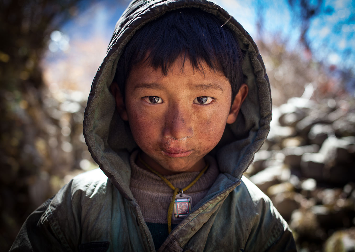 A young Tibetan boy stares into the camera with curiosity.