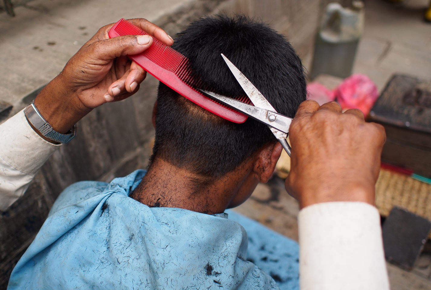 A street barber giving a haircut to one of the locals.