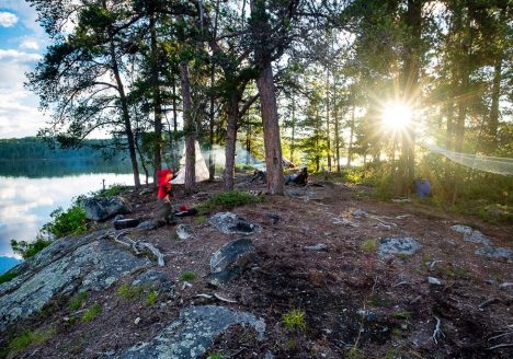 campsite on Obabika Inlet with hammock and boy playing in the background